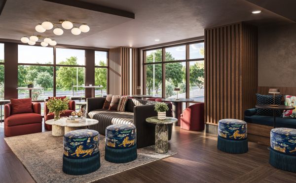 Modern living room with large windows, brown sofa, patterned stools, and wooden accents, filled with natural light.